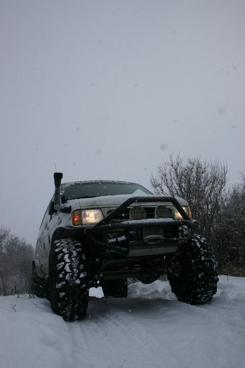 2003 Jeep TJ - Modified off-road vehicle navigates snowy terrain with a snorkel intake.