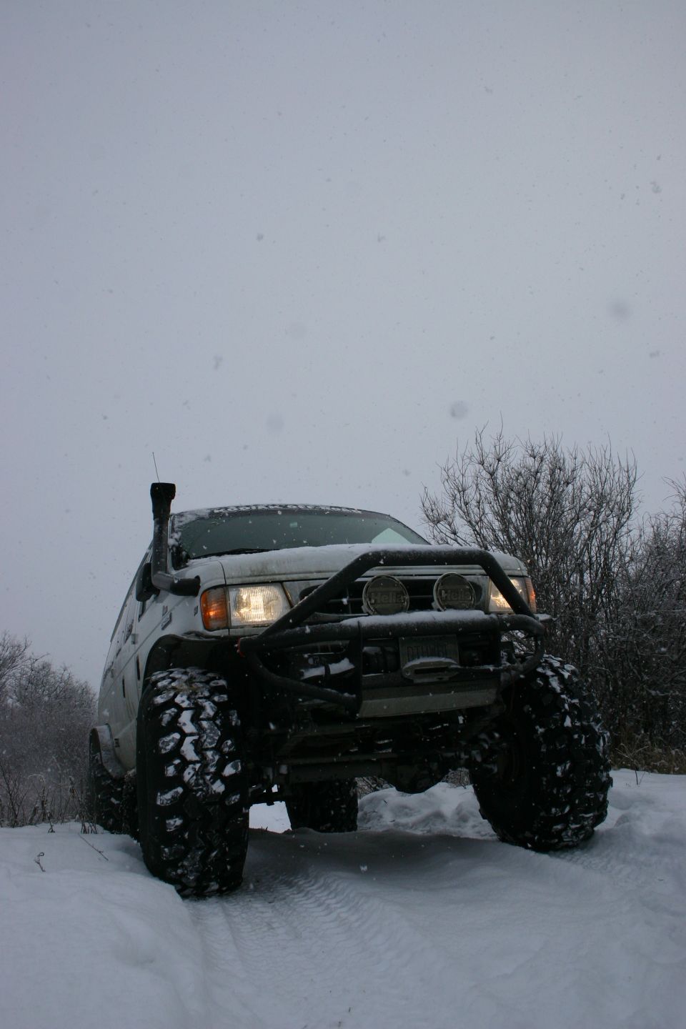 Off-road vehicle with large tires and snorkel driving in snow