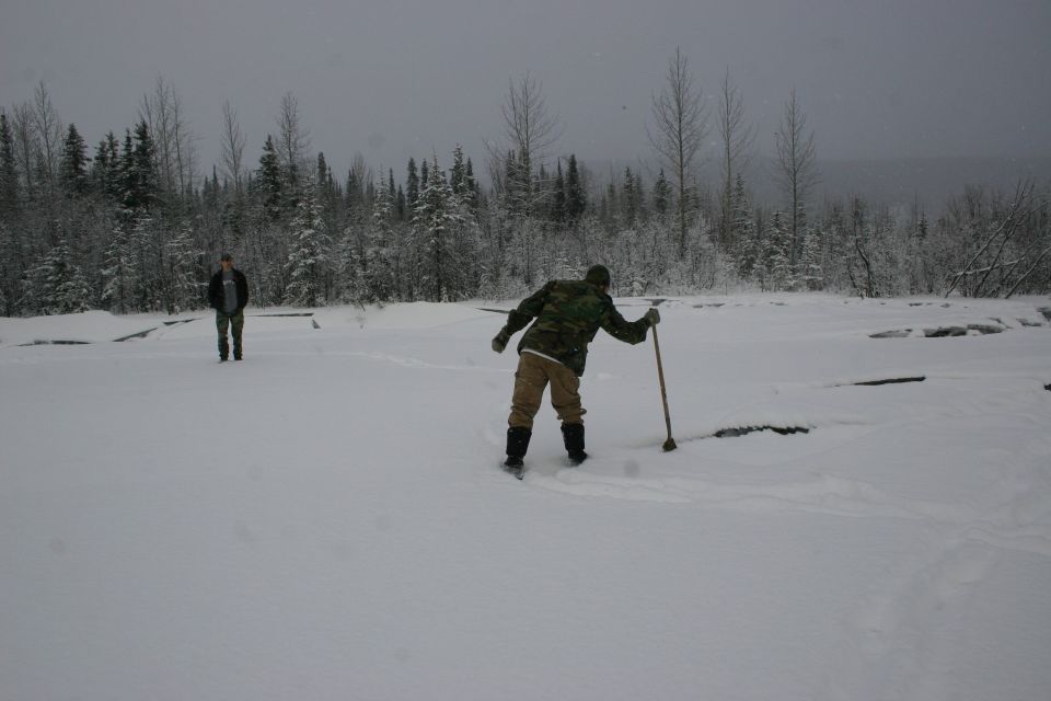 Two people in a snowy field with trees behind them