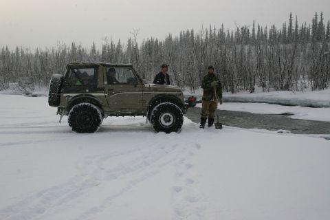2003 Jeep TJ - Two people and an off-road vehicle are in a snowy environment next to a river.