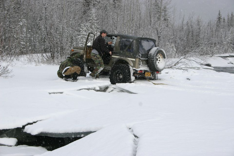 2003 Jeep TJ with soft top in snow, driver getting out, near icy water