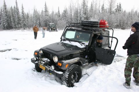 2003 Jeep TJ - A black Jeep Wrangler is stuck in deep snow, with a winch on the front and a roof rack loaded for an expedition.