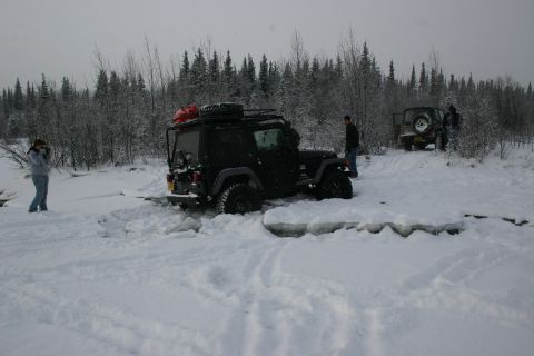 2003 Jeep TJ - Two Jeep Wranglers navigate a snowy trail, one appears stuck in the ice and snow.