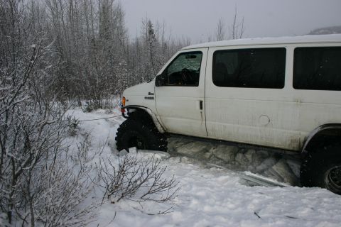 2003 Jeep TJ - White van with large tires stuck in snow, being pulled by a rope.