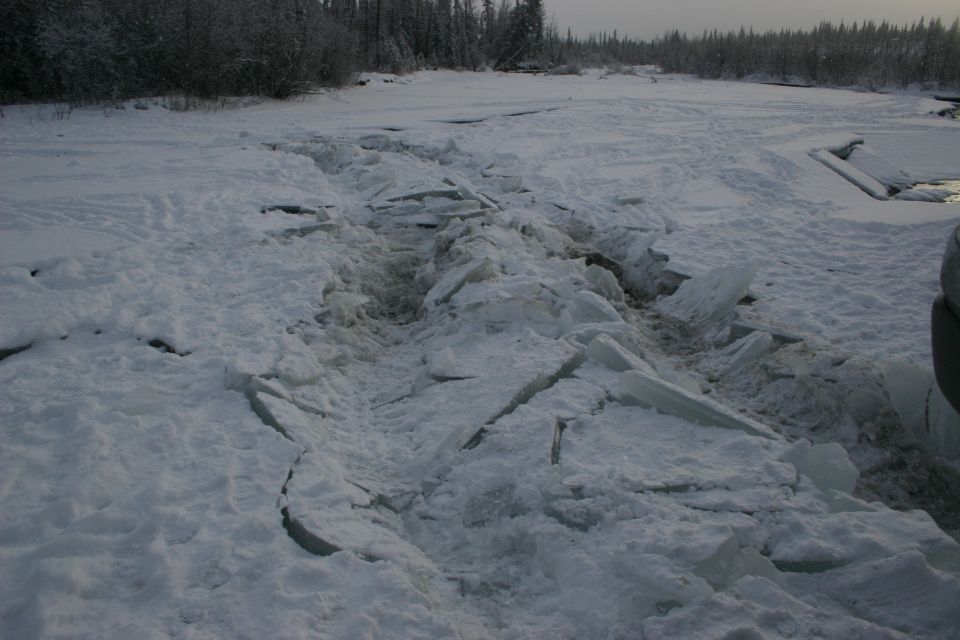 Vehicle partially visible on right, driving through broken ice and snow