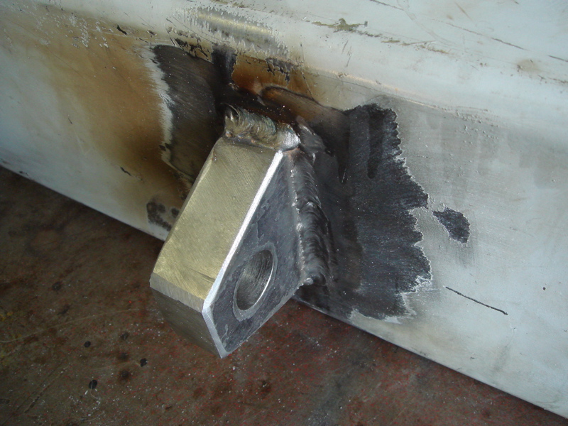 Welded metal bracket attached to a beam, showing weld marks and metal discoloration
