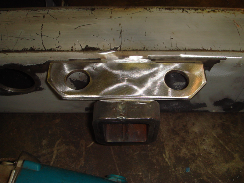 Close-up of a welded metal bracket with two circular holes, attached to a vehicle bumper