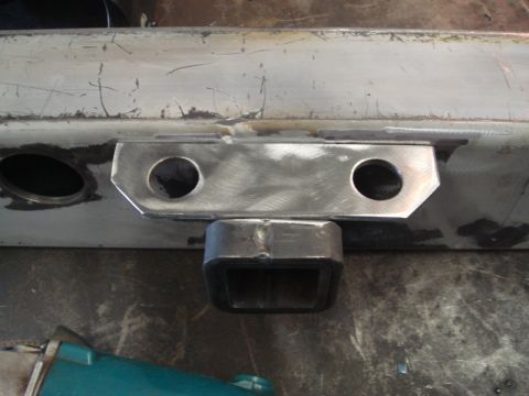 1996 Ford Bronco - A custom trailer hitch receiver is welded onto a metal frame, showing two bolt holes and a square receiver tube.