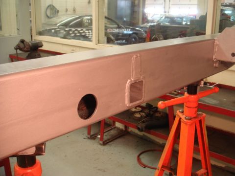 1996 Ford Bronco - A metal bumper beam is shown supported by an orange jack stand in a workshop setting.