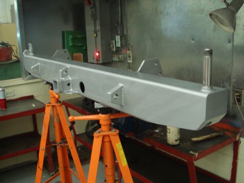 1996 Ford Bronco - A freshly painted rear bumper assembly is supported by jack stands in a workshop environment.