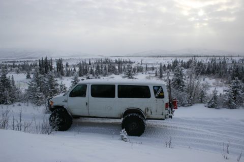 2003 Jeep TJ - Modified van with oversized tires navigates a snowy, wooded terrain under an overcast sky.