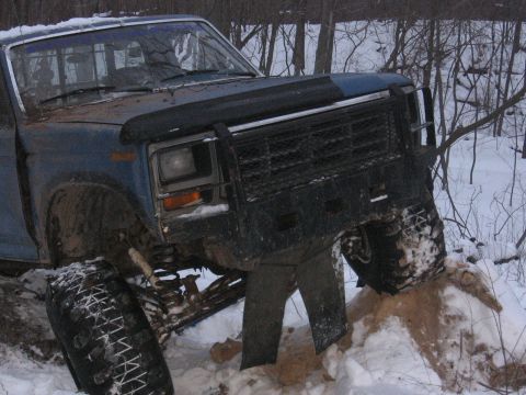 1979 Ford Bronco - A blue pickup truck is stuck in the snow with its front end elevated.