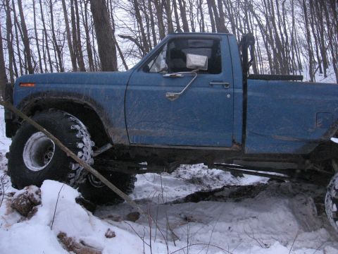 1979 Ford Bronco - Blue pickup truck with large tires navigating snowy terrain.