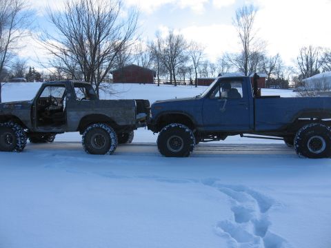 1979 Ford Bronco - Two lifted trucks, a Bronco and a pickup, sit in the snow on a winter day.
