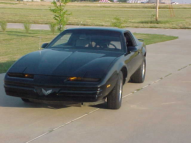 Black 1985 Pontiac Firebird coupe parked on a paved surface, front-left quarter view