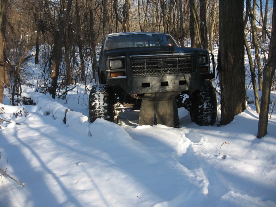 Front view of a heavily modified truck with large tires stuck in deep snow