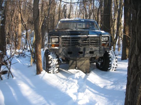 1979 Ford Bronco - Pickup truck with aftermarket bumper and large tires sits in a snowy wooded area.