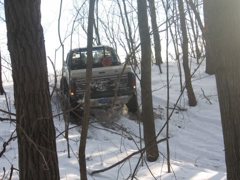 1979 Ford Bronco - A white pickup truck navigates a snowy, wooded trail.