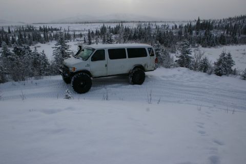 2003 Jeep TJ - Modified van navigates a snow-covered landscape with dense trees in the background.