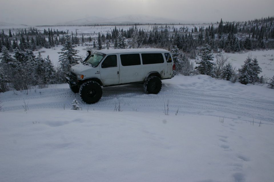 White van with oversized tires and snorkel on snowy terrain