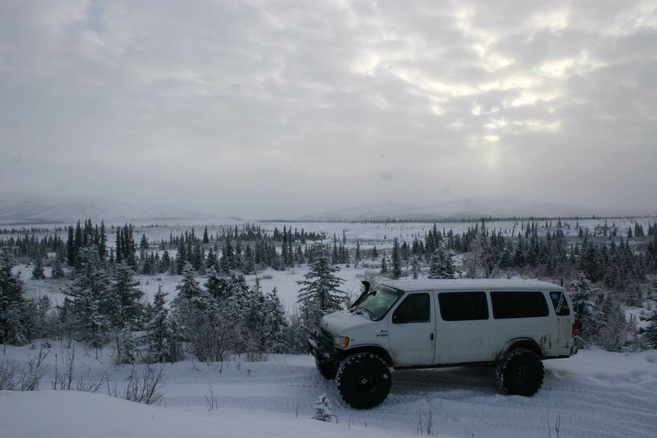 White van with large tires parked in snow, snorkel on windshield