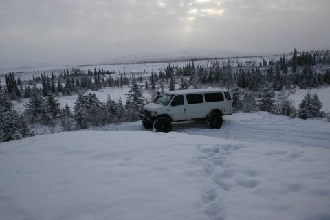2003 Jeep TJ - A white van modified for off-road use sits in a snowy, wooded landscape under a cloudy sky.