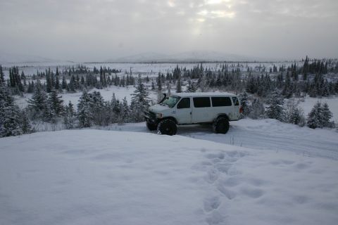 2003 Jeep TJ - A modified white van sits in a snowy landscape with a dense forest in the background under an overcast sky.