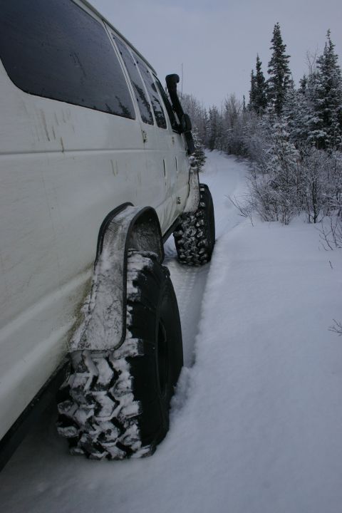 2003 Jeep TJ - White van with snorkel and large tires navigates a snowy forest trail.