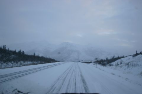 2003 Jeep TJ - Driving on a snow-covered highway with mountains in the distance.