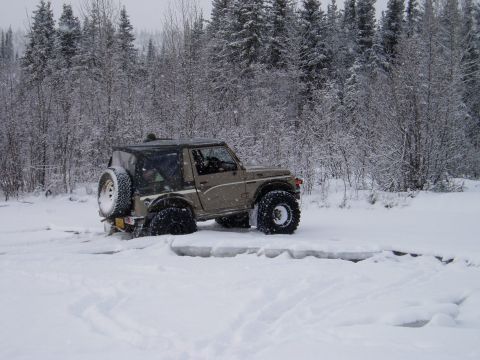 2000 Ford E350 - Off-road vehicle stuck in snow with trees in the background.