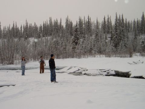 2000 Ford E350 - A group of people are in a snowy landscape with a forest and river.