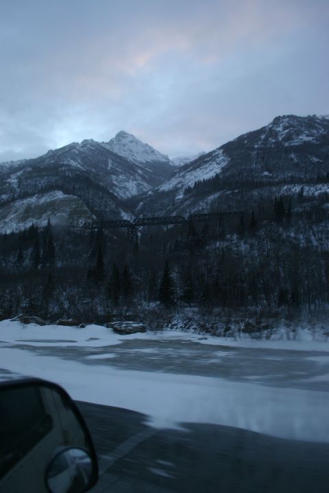 2003 Jeep TJ - A view from a vehicle's side mirror shows a winter scene with snow-covered mountains and a partially frozen river.