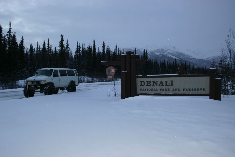 White van with large tires in snow near Denali National Park sign