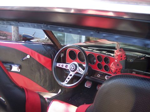 1972 Ford Ranchero - The interior features custom red and black upholstery, an aftermarket steering wheel, and a vibrant red dashboard with multiple gauges.
