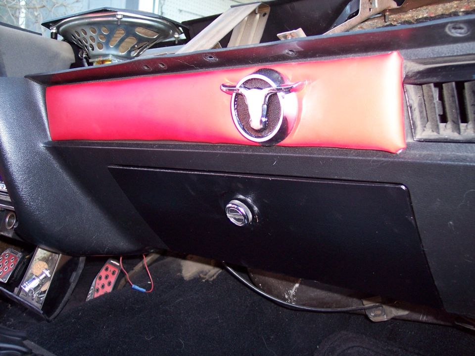 Red vinyl dash pad with chrome longhorn emblem above black glovebox door
