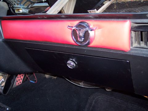 1972 Ford Ranchero - Close-up of a vehicle's dashboard interior, red trim and a distinctive chrome bull emblem.