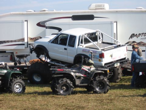 1974 Ford F-100 - Side view of a white extended-cab compact pickup built as a mud/race truck, with an external tube roll cage over the bed, diamond-plate bed…
