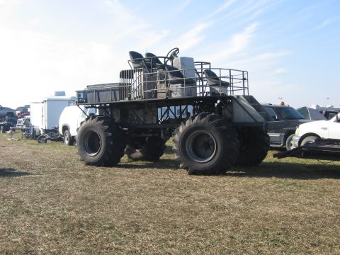1974 Ford F-100 - Rear three-quarter view of a home-built swamp buggy: a bare steel-tube chassis with an open platform deck, tall pedestal seats behind a rai…
