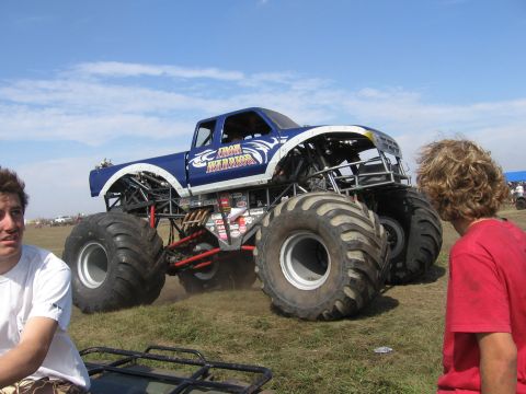 1974 Ford F-100 - Blue and white monster truck lettered 'Iron Warrior' with tribal graphics rolls across a dry grass field on huge terra-style flotation tire…