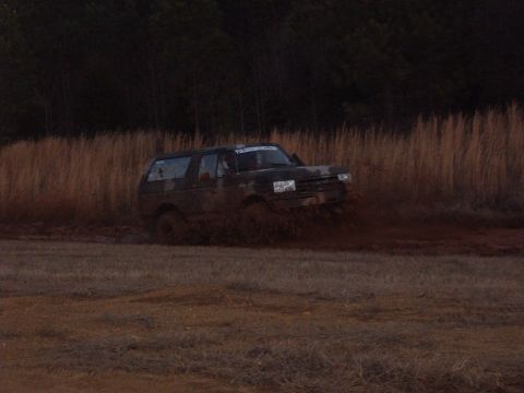 1988 Ford Bronco - This Ford Bronco is navigating a muddy terrain, with its tires splashing through the thick mud.