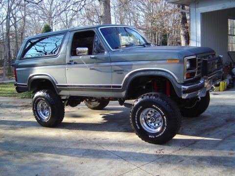 1986 Ford Bronco - Three-quarter front view of a two-tone gray 1980s full-size Ford Bronco with removable hardtop, lifted on BFGoodrich Radial T/A tires and p…