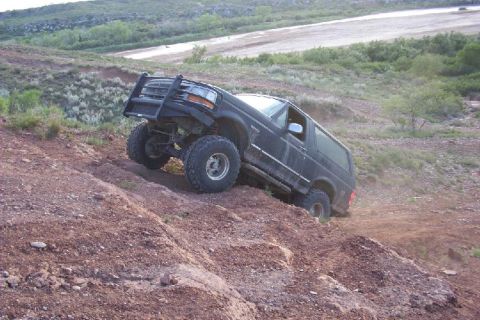1995 Ford Bronco - This 1995 Ford Bronco navigates a challenging, dusty incline in a rural, hilly landscape.