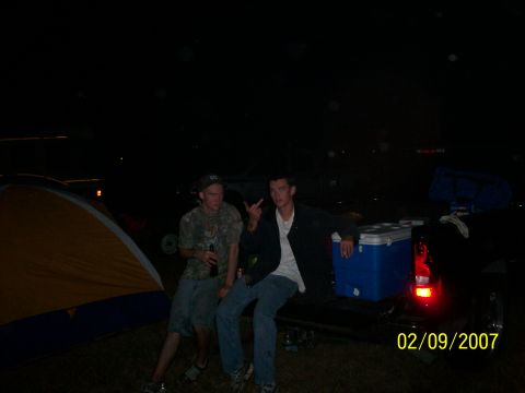 1974 Ford F-100 - Two men relax in the bed of a pickup truck at night, with a tent and cooler visible.