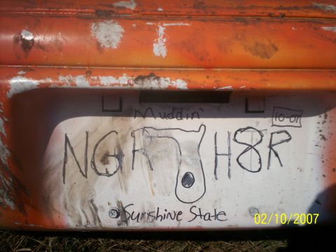 1974 Ford F-100 - A close-up of a dirty orange bumper shows a crudely drawn license plate with "Muddin'" written above it.