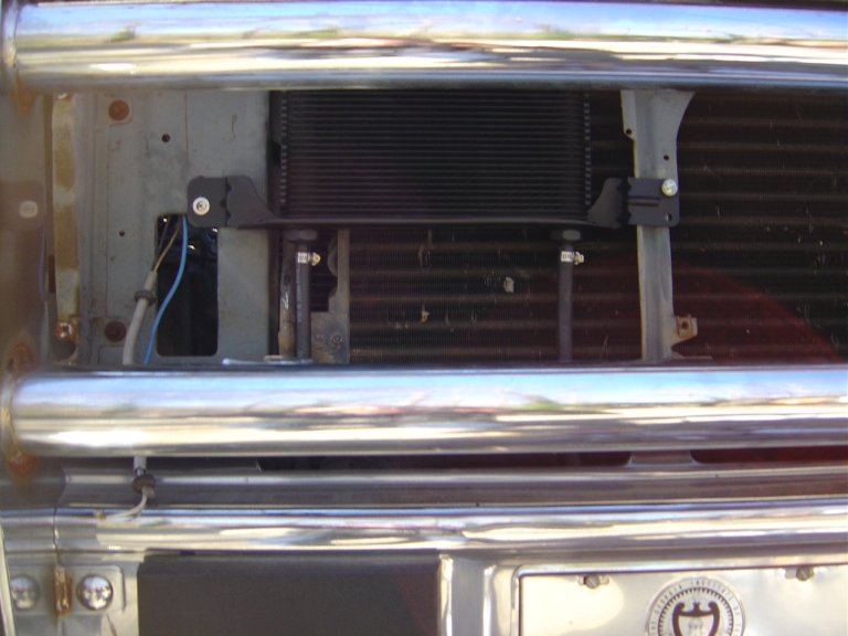 Black auxiliary transmission cooler mounted behind chrome grille bars in front of condenser