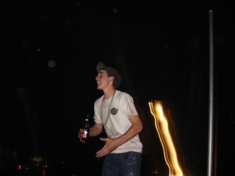 1974 Ford F-100 - Man with a beer bottle and beads at night, with blurred lights in the background.