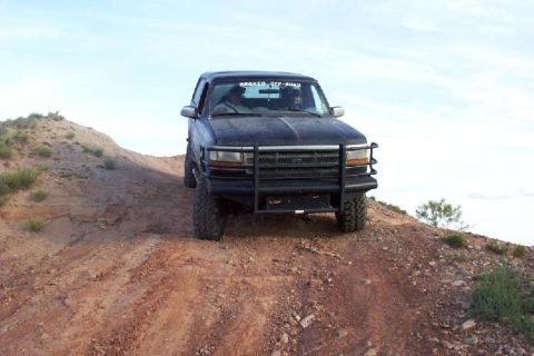 1995 Ford Bronco - A black 1995 Ford Bronco is parked on a dirt hill under a clear sky.