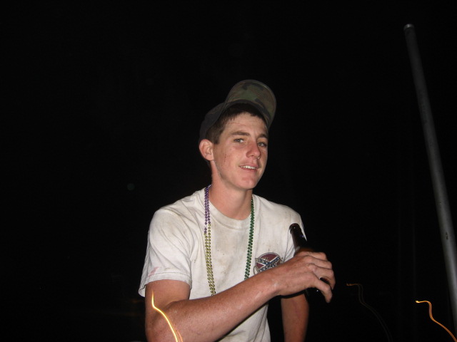 guy wearing beads and holding a beer bottle, wearing a cap backwards