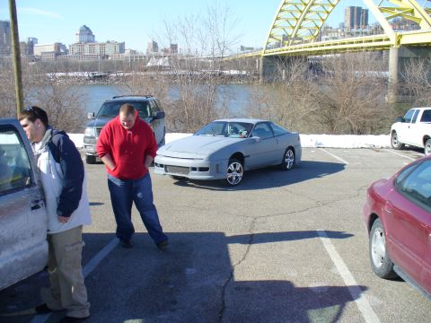 1991 Ford Probe - A gray coupe sits in a parking lot with a bridge and city skyline in the background.