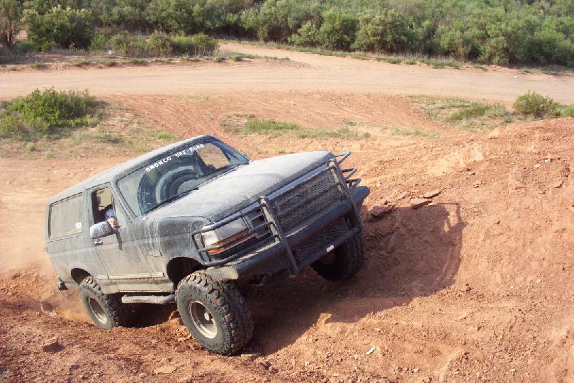 Gray Ford Bronco with brush guard climbing a dirt hill off-road
